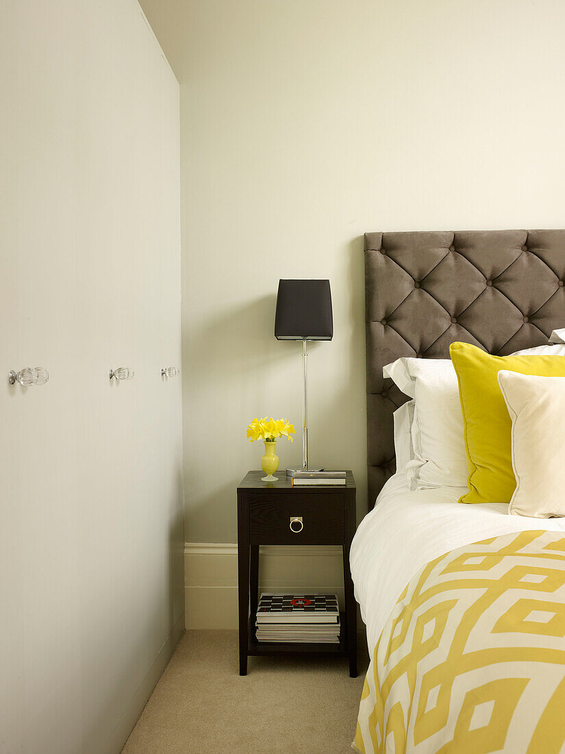 Black lamp on side table with geometric bed cover and buttoned headboard in Little Venice townhouse London England UK