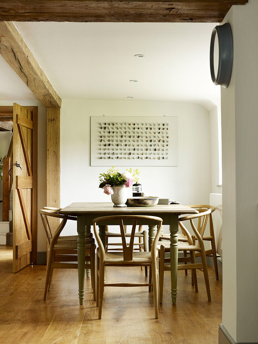 Roses in vase on dining table with chairs in West Sussex farmhouse, England, UK