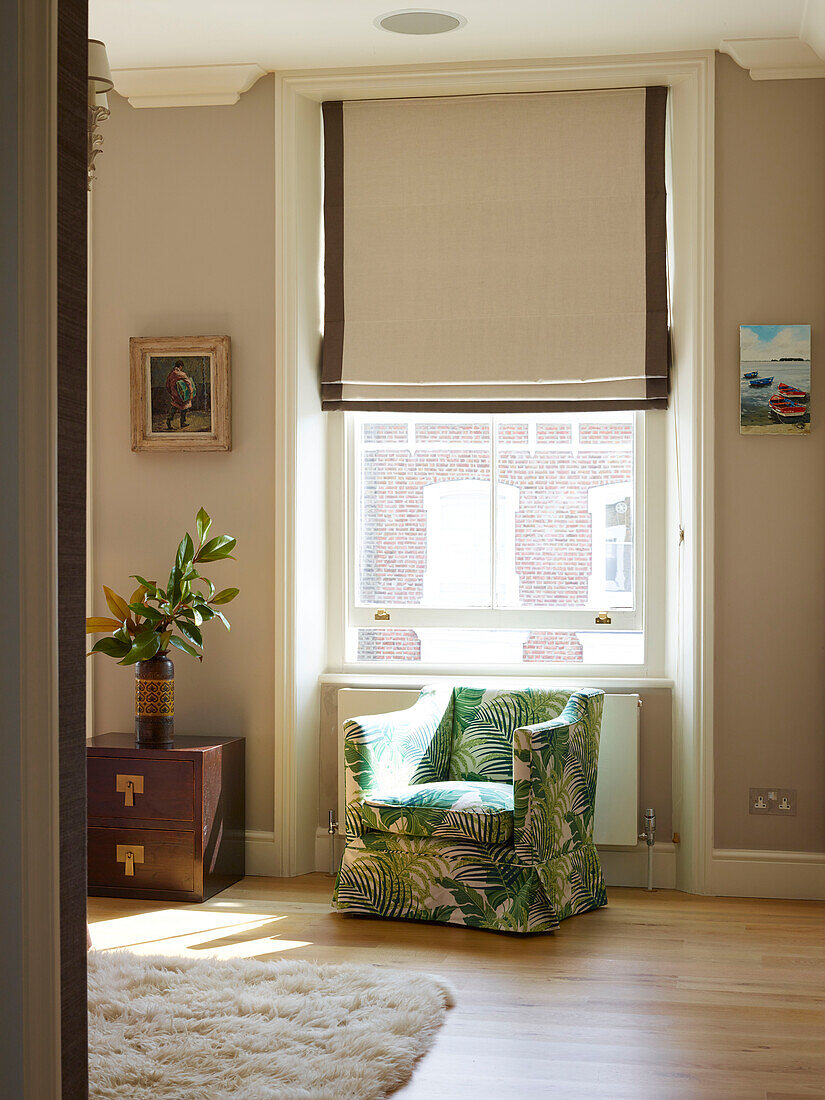 Gepolsterter Sessel am sonnendurchfluteten Fenster in einem Londoner Stadthaus, UK