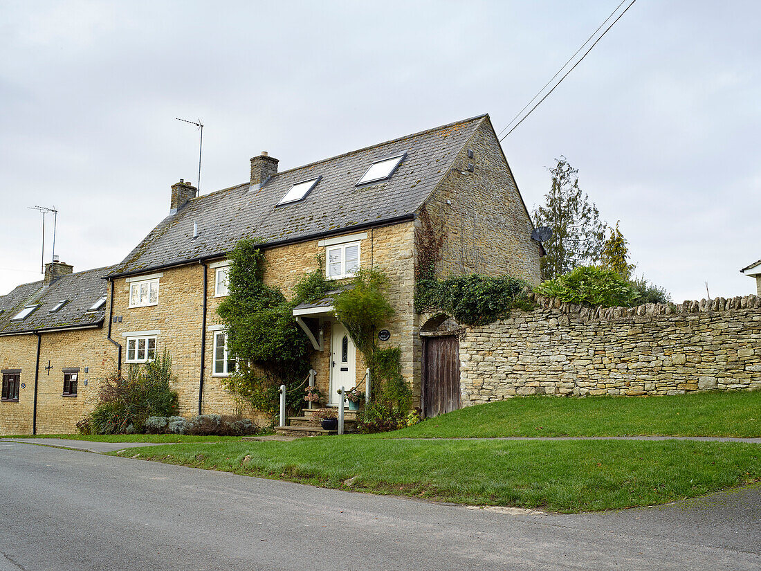 Oxfordshire stone cottage with climbing plant above porch, England, UK