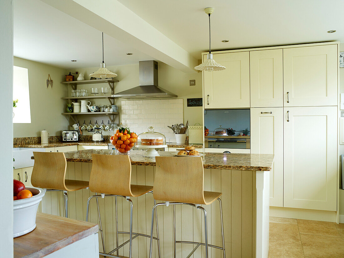 Wood and chrome stools at breakfast bar in open plan Oxfordshire kitchen, England, UK