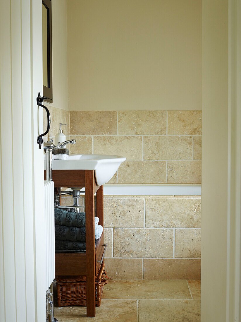 View through doorway to wooden washstand in tiled bathroom of Oxfordshire cottage, England, UK