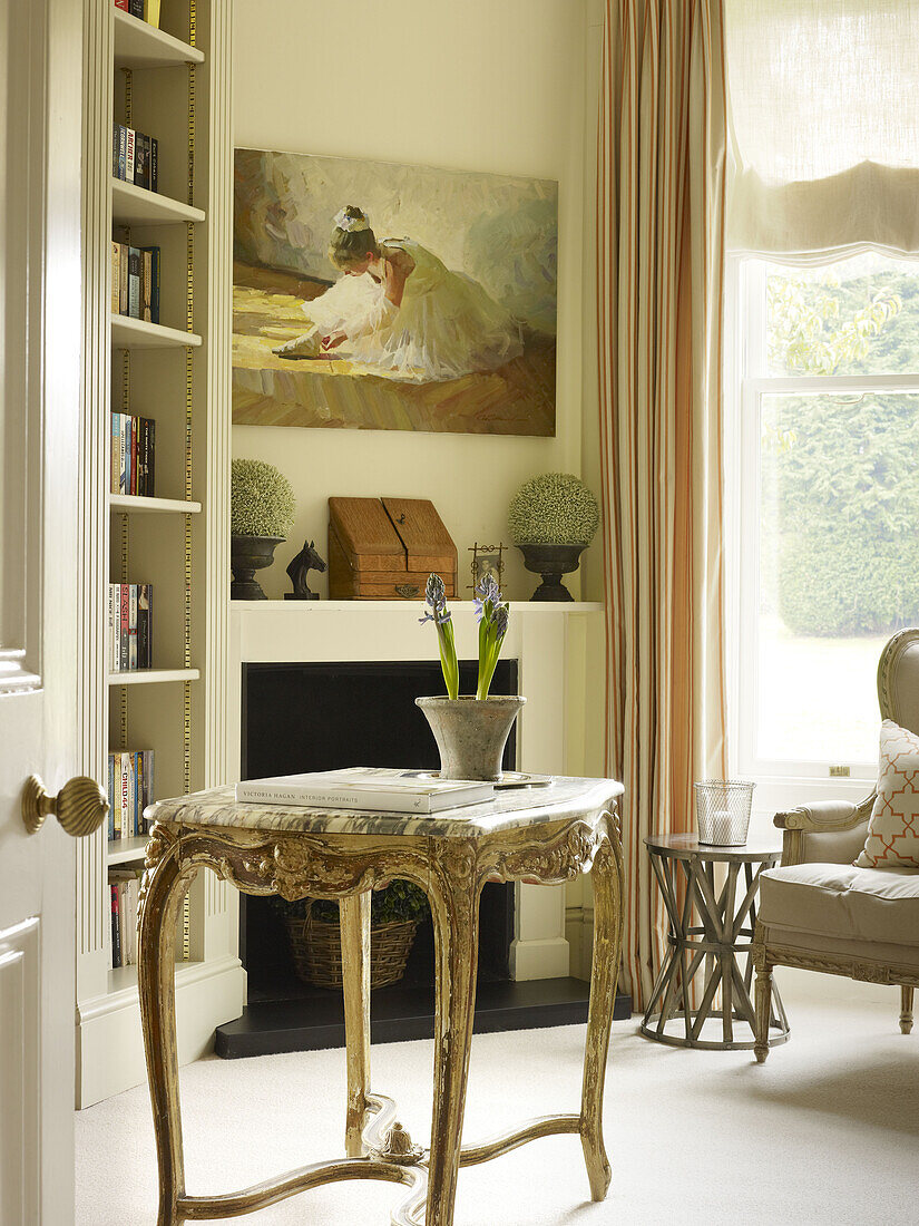 Marble topped antique side table and bookcase in East Sussex country house England UK