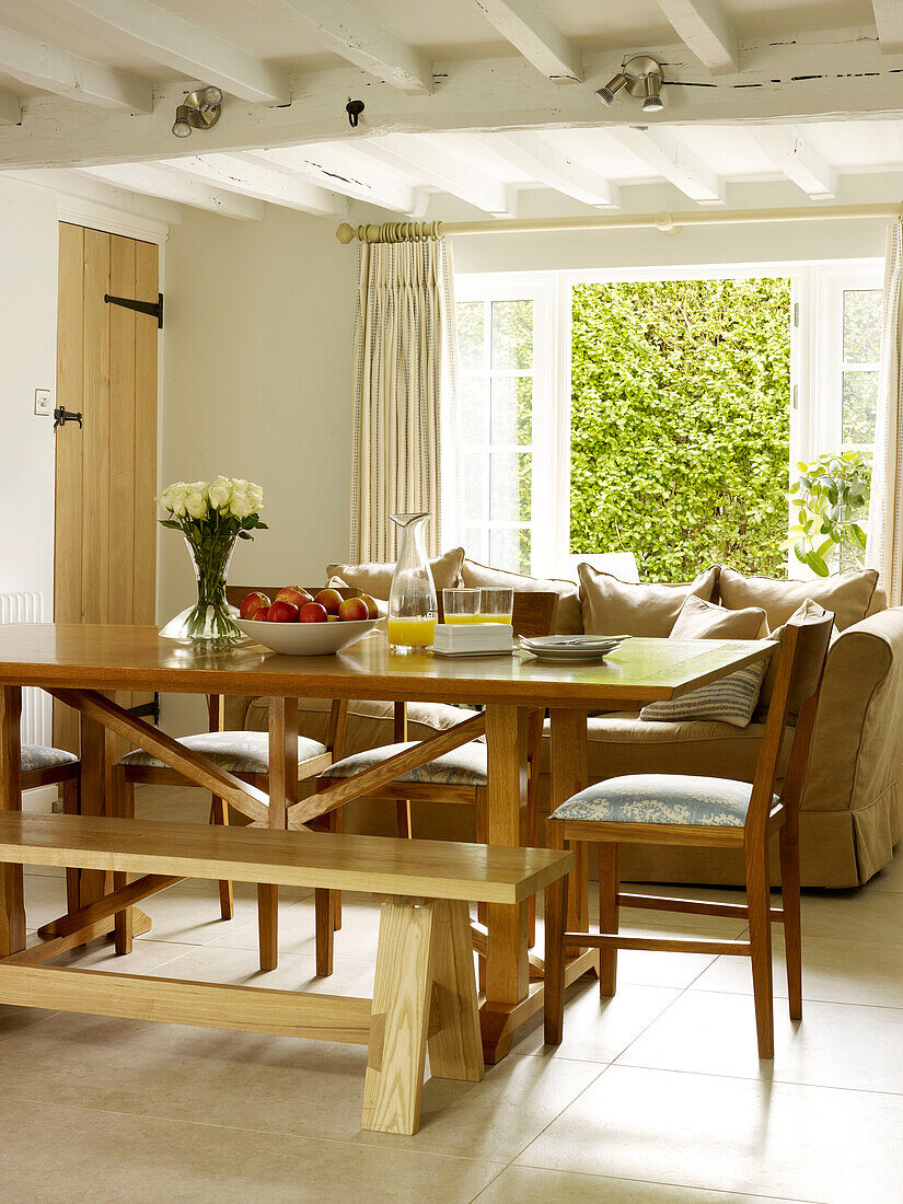 Esstisch und Stühle aus Holz mit Sofa und offenen Terrassentüren in einem Haus in Nottinghamshire England UK