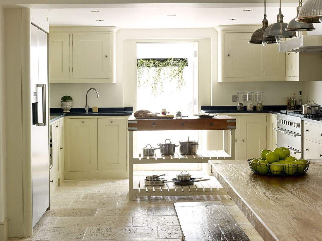 Saucepans on butlers block in tiled cream fitted kitchen of North London townhouse England UK