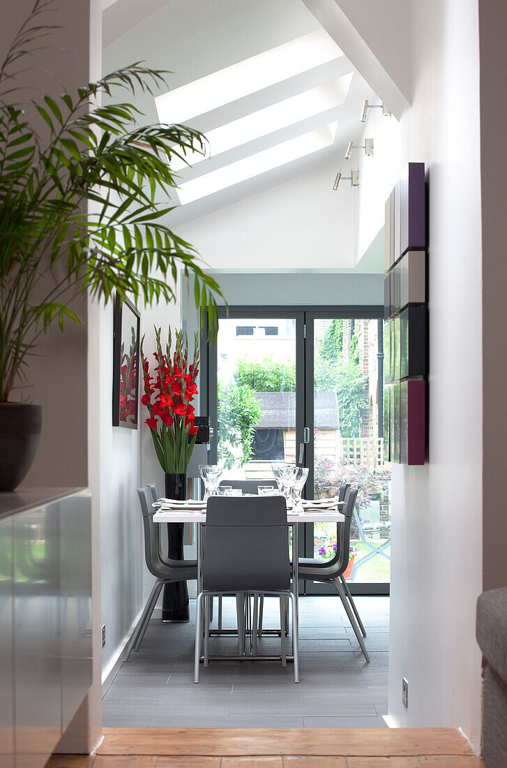 Blick durch den Flur zum grauen Esszimmer unter den Dachfenstern in einem modernen Haus in London, England, UK