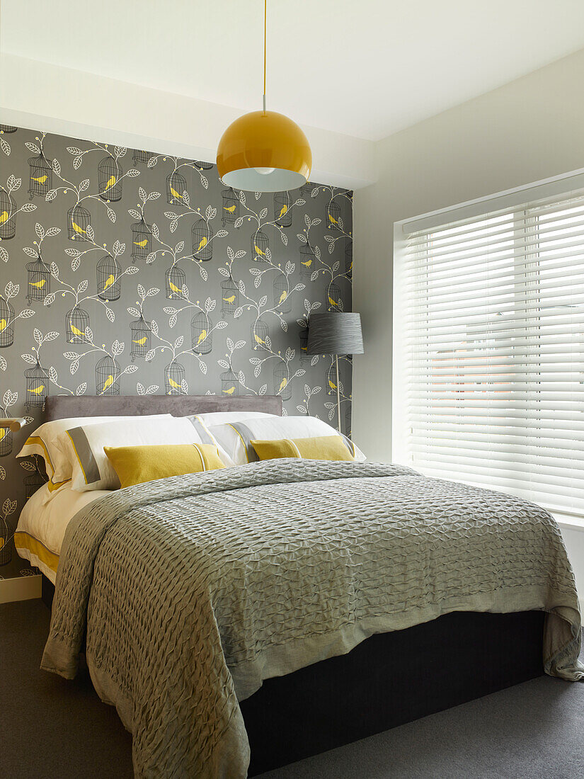 Grey and yellow bedroom with bird and leaf patterned wallpaper in Manchester home, England, UK