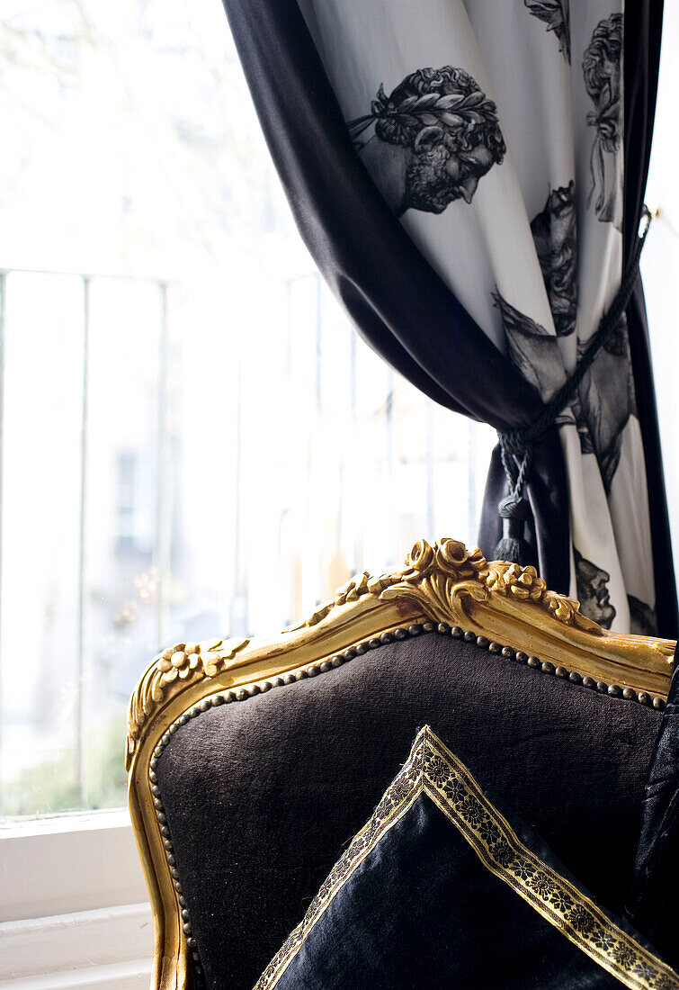 Black gilded chair and curtains with tie-backs at window of Hove home East Sussex UK