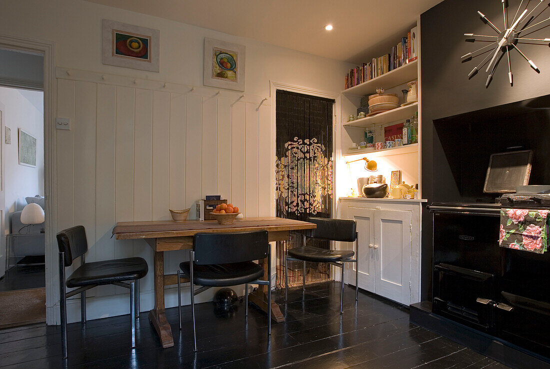 Black leather chairs at table in kitchen of London home UK