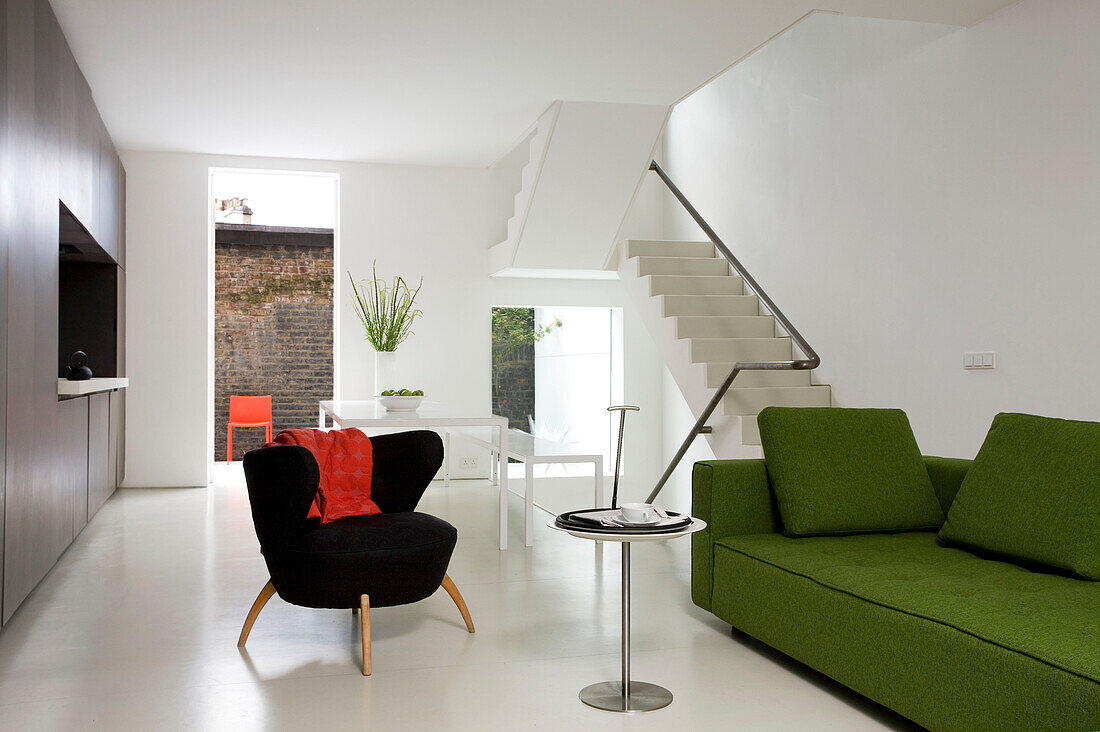 Lime green sofa and small black chair in open plan interior of contemporary London apartment, England, UK