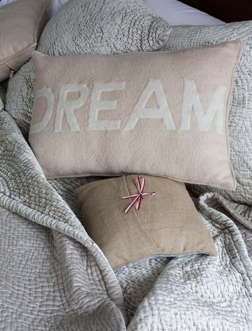 Cushion with the word 'Dream' on light blue quilt London UK