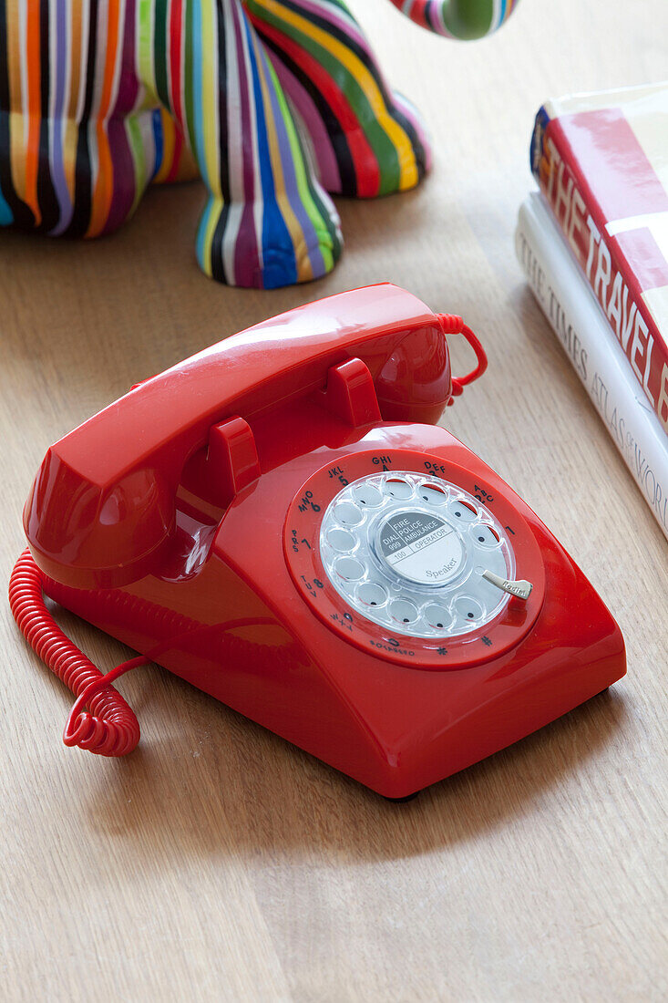 Rotes Kunststofftelefon mit Wählscheibe auf dem Couchtisch in einem modernen Haus in London, Vereinigtes Königreich