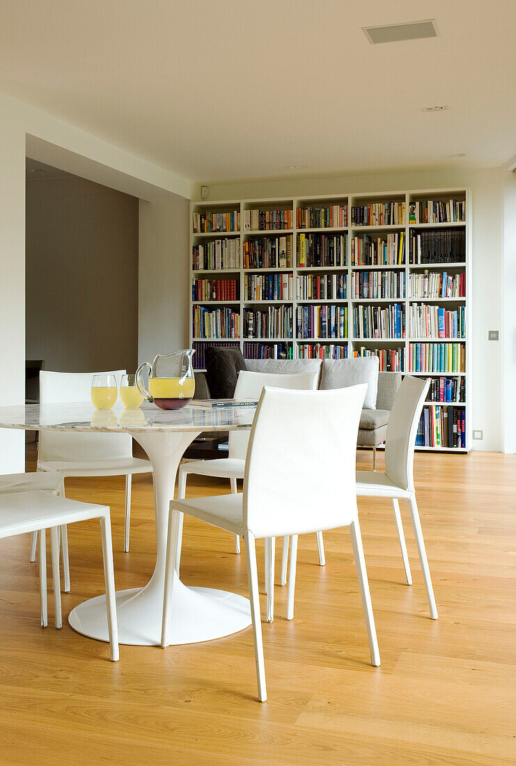 Pedestal base table and chairs with bookcase shelving in London home, England, UK