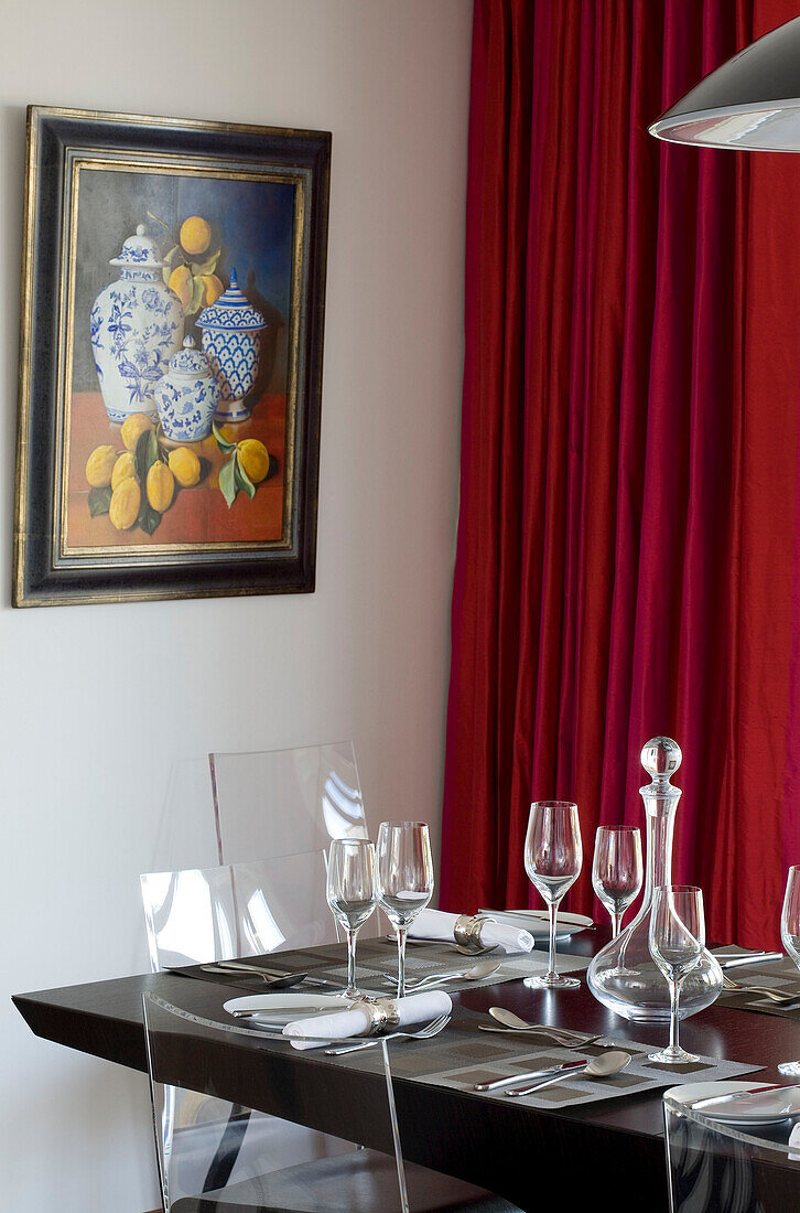 Glassware and artwork with red curtains in dining room of Newmarket home Suffolk UK