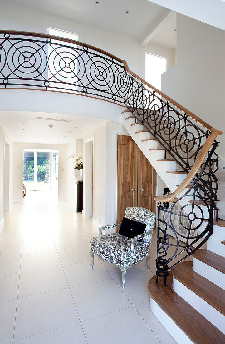 Black and white armchair under wrought iron staircase in Hendon home London UK