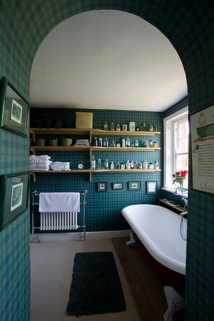 View through arched doorway to bathroom of Suffolk home with shelves of toiletries UK