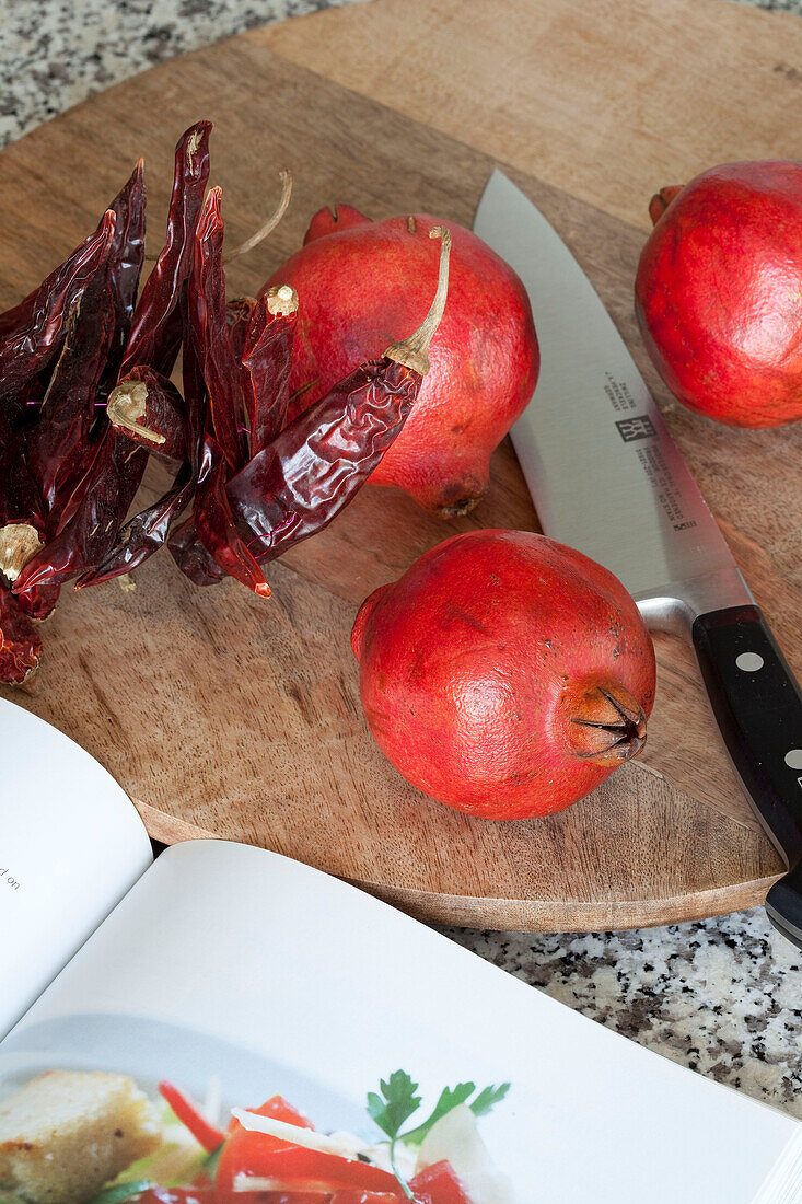 Schneidebrett mit Messer Granatapfel und Chili