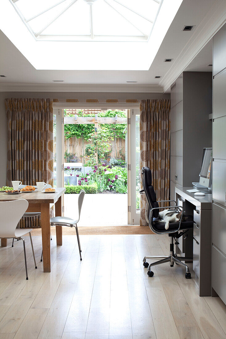 Office chair at desk and table in open plan extension of contemporary London home, UK