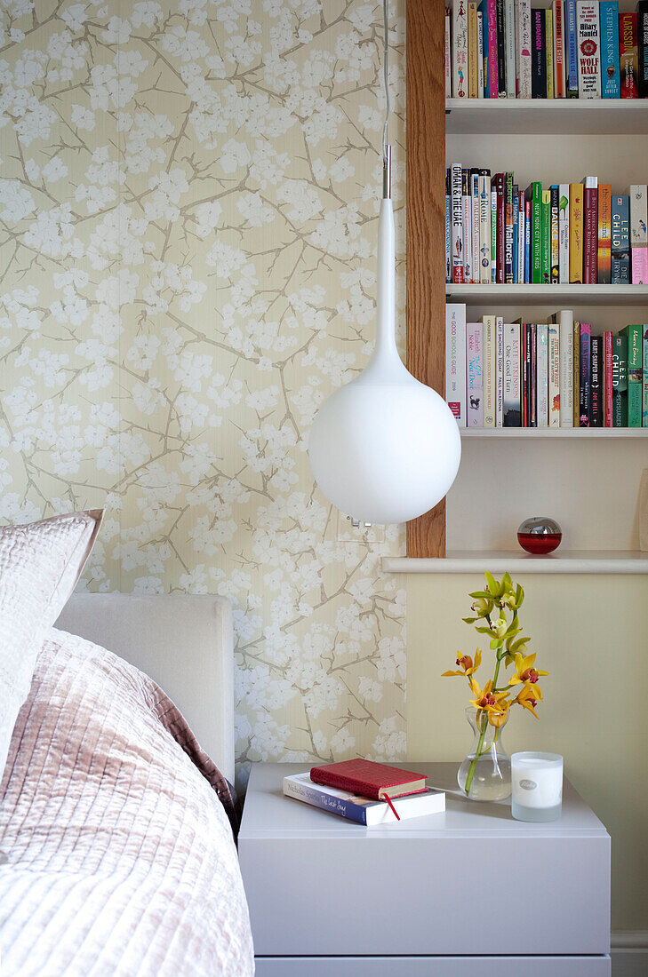 Eingelassene Bücherregale und Pendelleuchte am Bett in einer modernen Wohnung in London, Großbritannien