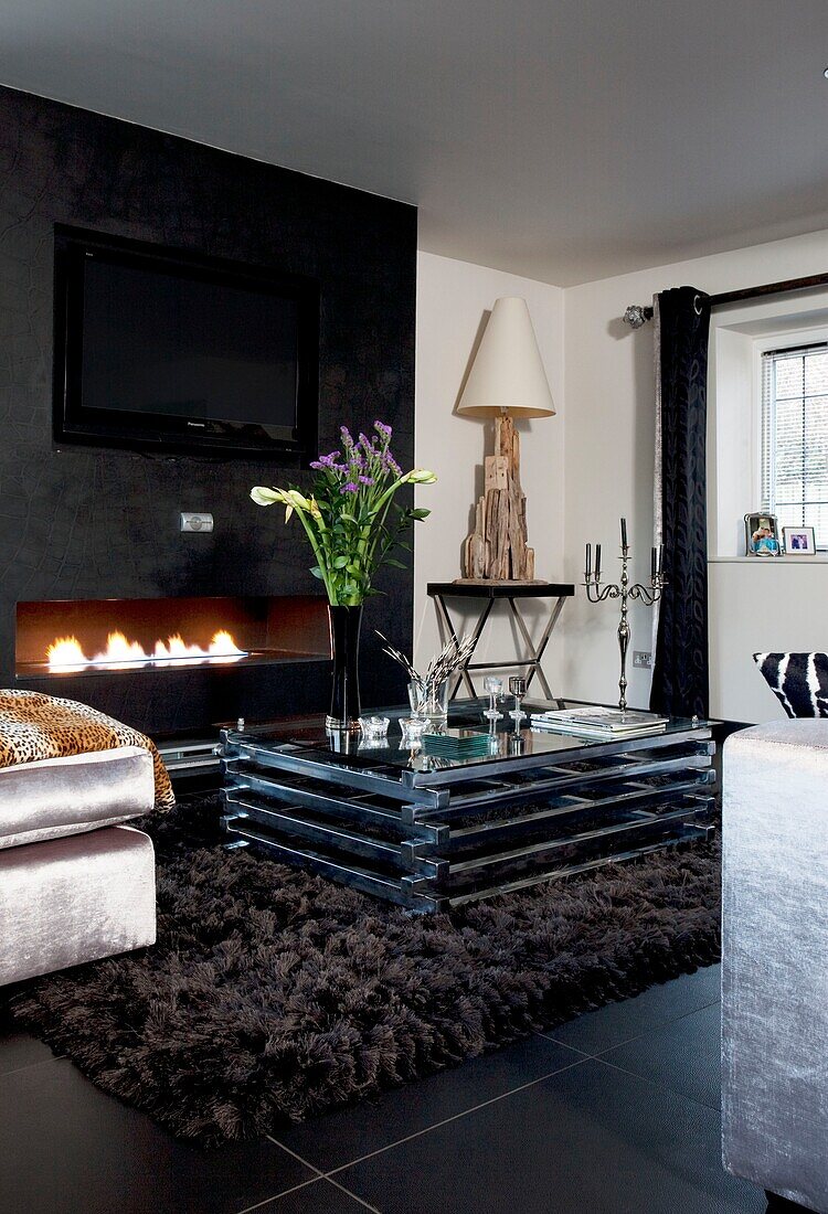 Glass coffee table and open fire with plasma screen TV in contemporary London townhouse, UK