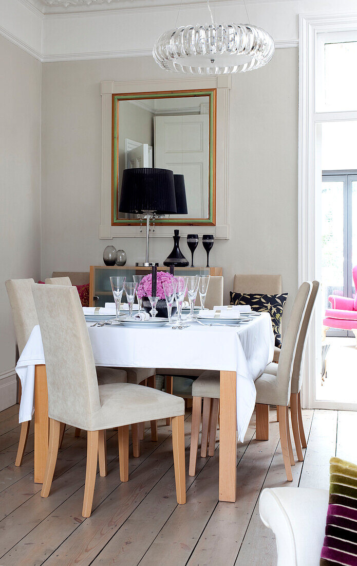 Glass pendant light above dining table with rectangular mirror in contemporary London home, UK