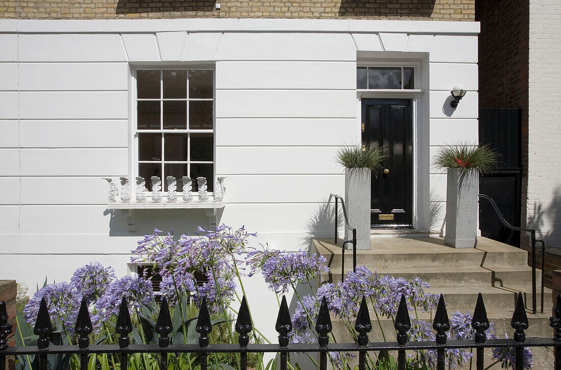 Black front door and railings of townhouse