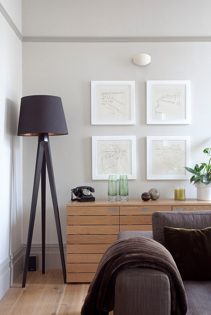 Brown standard lamp and artwork display above wooden sideboard n contemporary living room, Hove, East Sussex, England, UK