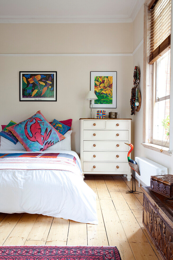 Modern artwork above bed in bedroom with wooden floorboards in London townhouse, England, UK