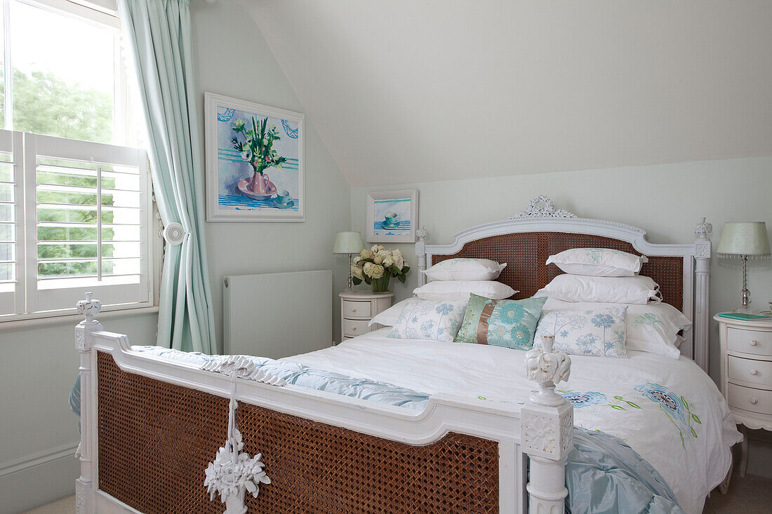 Antique wicker bed at window of pastel green bedroom in London home, UK