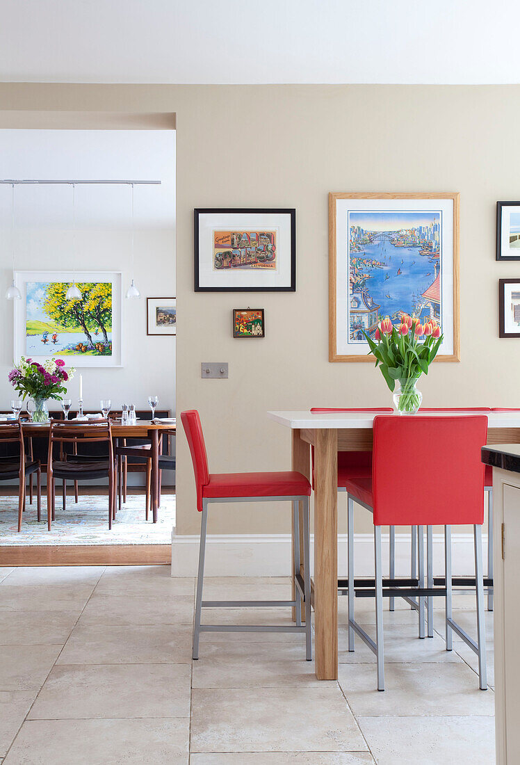 Red bar stools at breakfast bar in kitchen with view to dining area in Herefordshire family home England UK