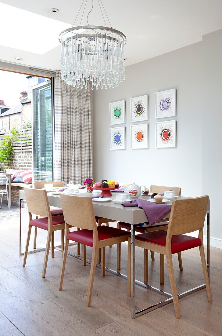 Dining table an chairs under glass chandelier in contemporary London townhouse, England, UK