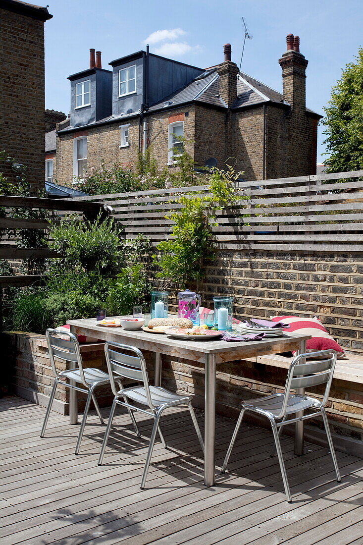 Table and chairs on wooden decking of contemporary London townhouse, England, UK