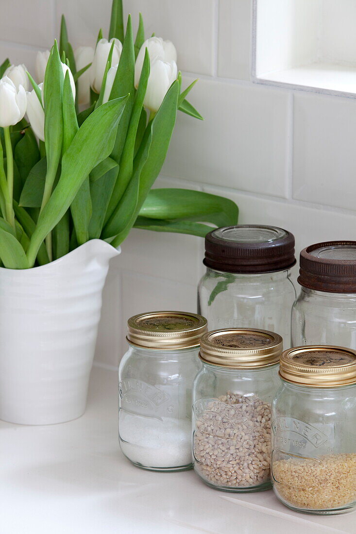 Storage jars and cut tulips in kitchen of London townhouse, England, UK