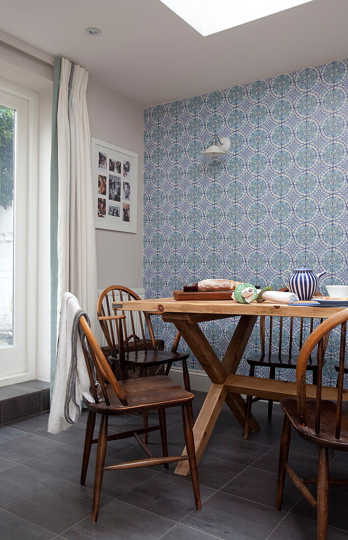 Esstisch und Stühle aus Holz mit blau gemusterter Tapete in einem Stadthaus in London, England, UK