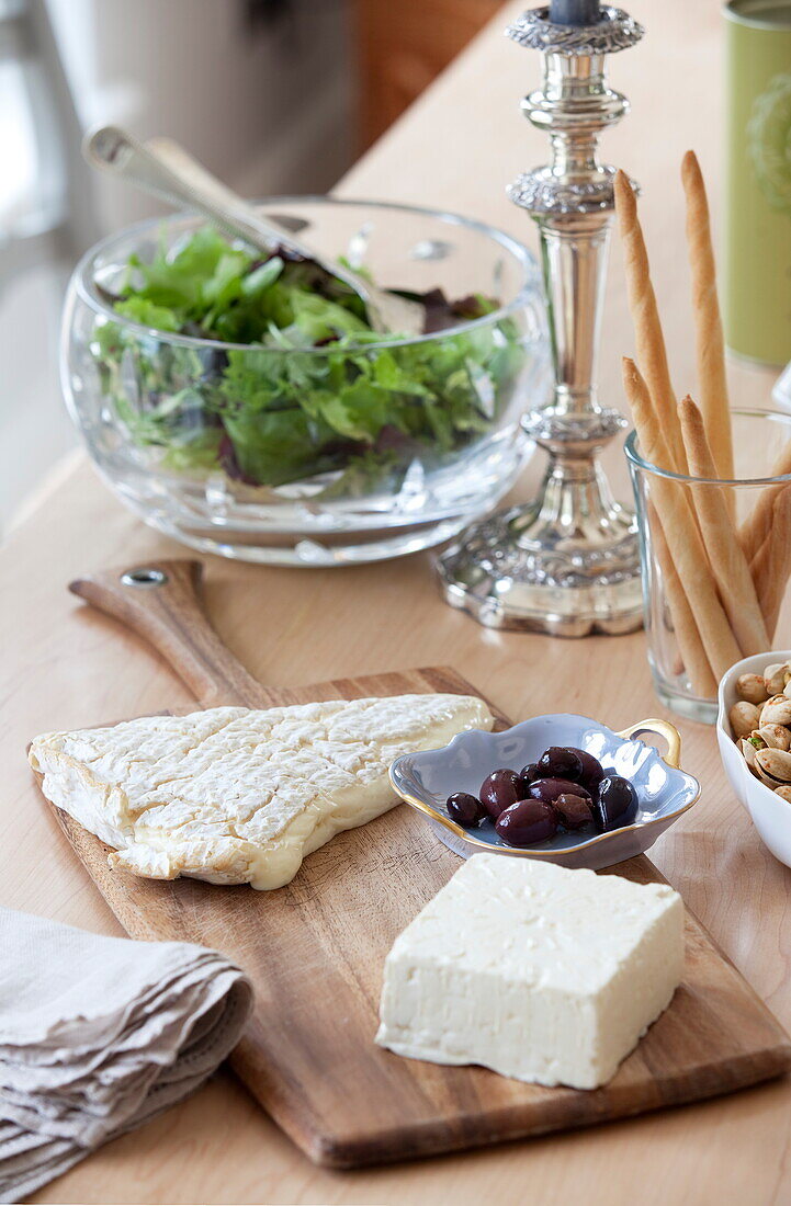 Cheeseboard and salad with breadsticks on wooden dining table in Maidstone farmhouse, Kent, England, UK