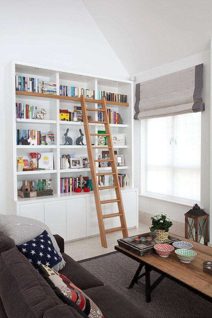 Bücherregal mit Zugangsleiter im Wohnzimmer eines modernen Landhauses in Surrey, England