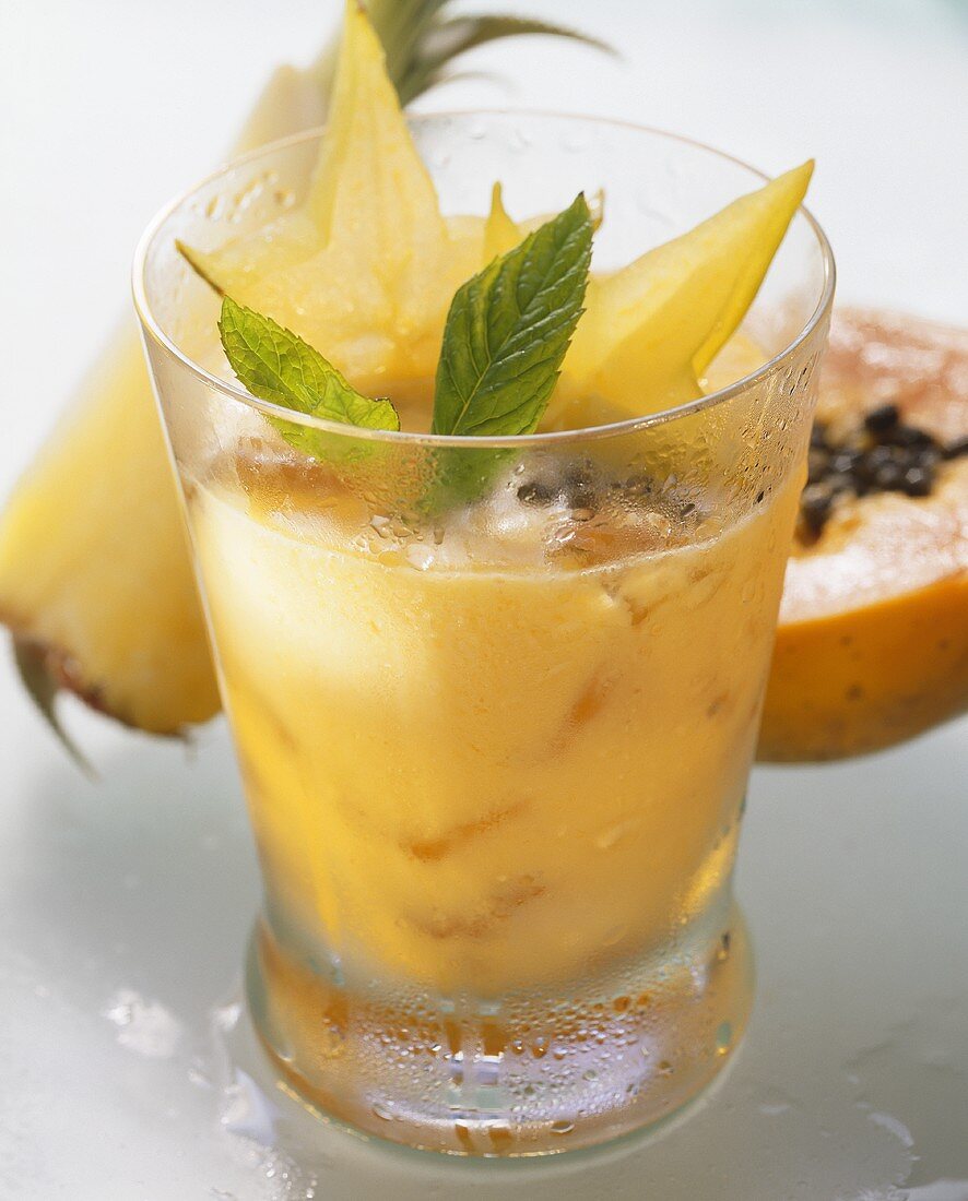 Papaya-Ananas-Drink, garniert mit Karambolesternen & Minze