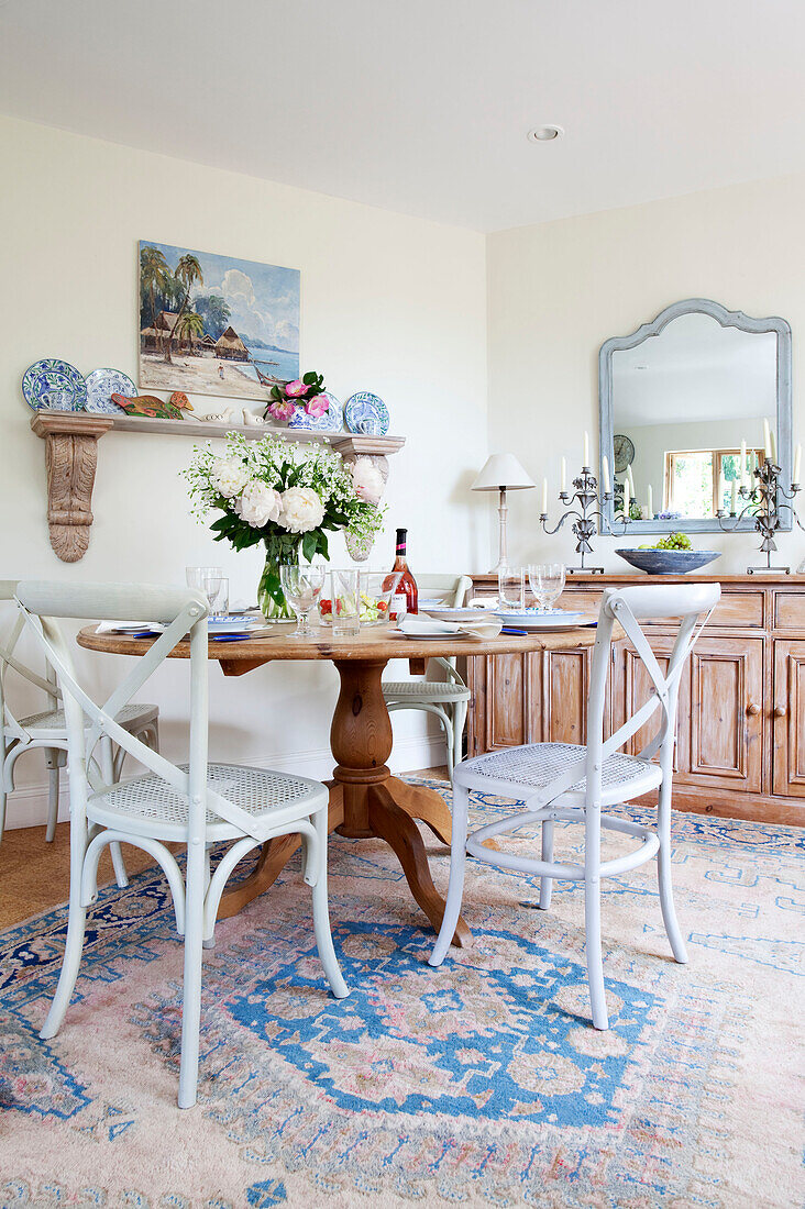 Painted wicker chairs at wooden dining table in Sussex cottage, England, UK