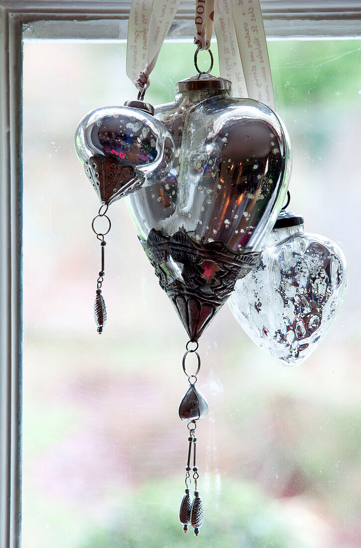 Vintage baubles hang in window of Surrey farmhouse, England, UK