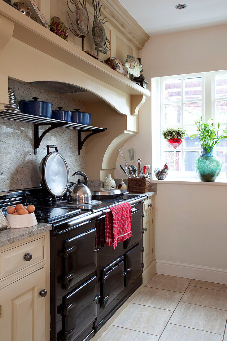 Kettle on hob of black range oven in Surrey farmhouse kitchen, England, UK