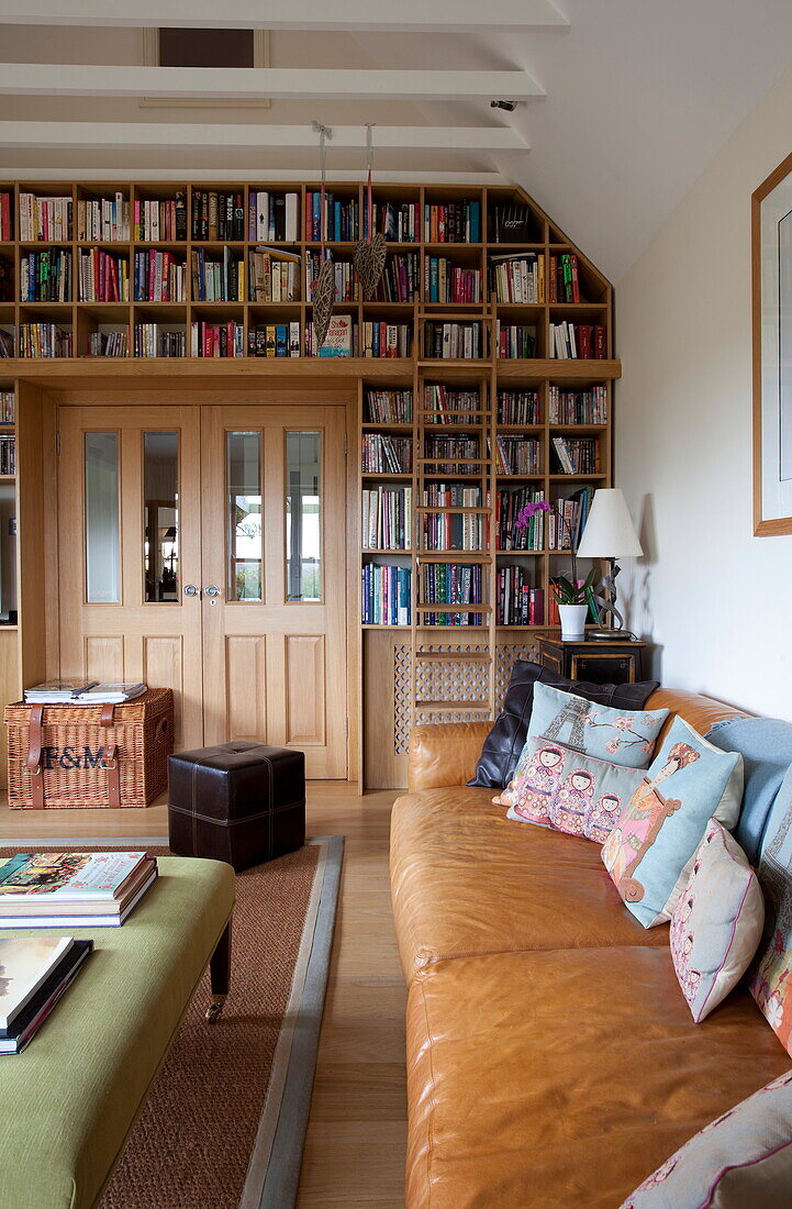 Tan leather sofa and bookcase in living room of Kent home, England, UK