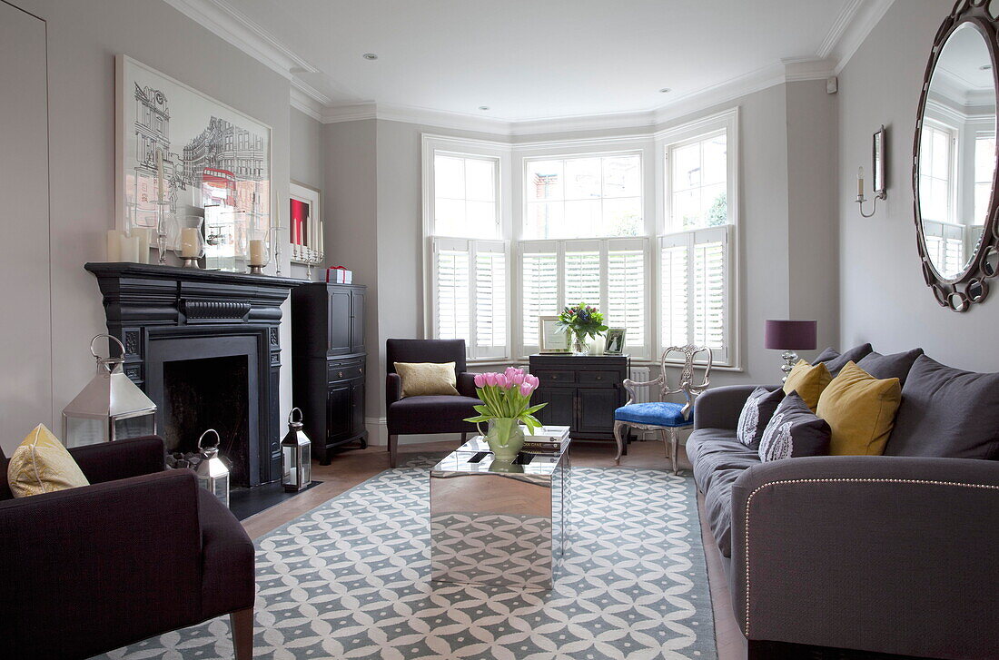 Shuttered bay window in living room with large mirror in London townhouse England UK