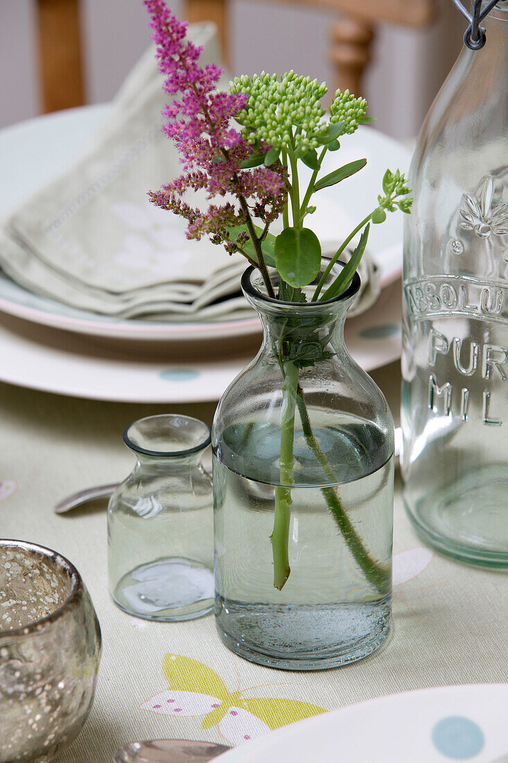 Cut flowers in vintage bottle on kitchen table in Sussex Downs home England UK