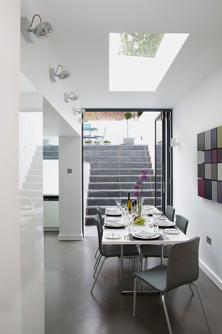 Grey dining chairs at table with modern artwork in contemporary Brighton home, East Sussex, England, UK