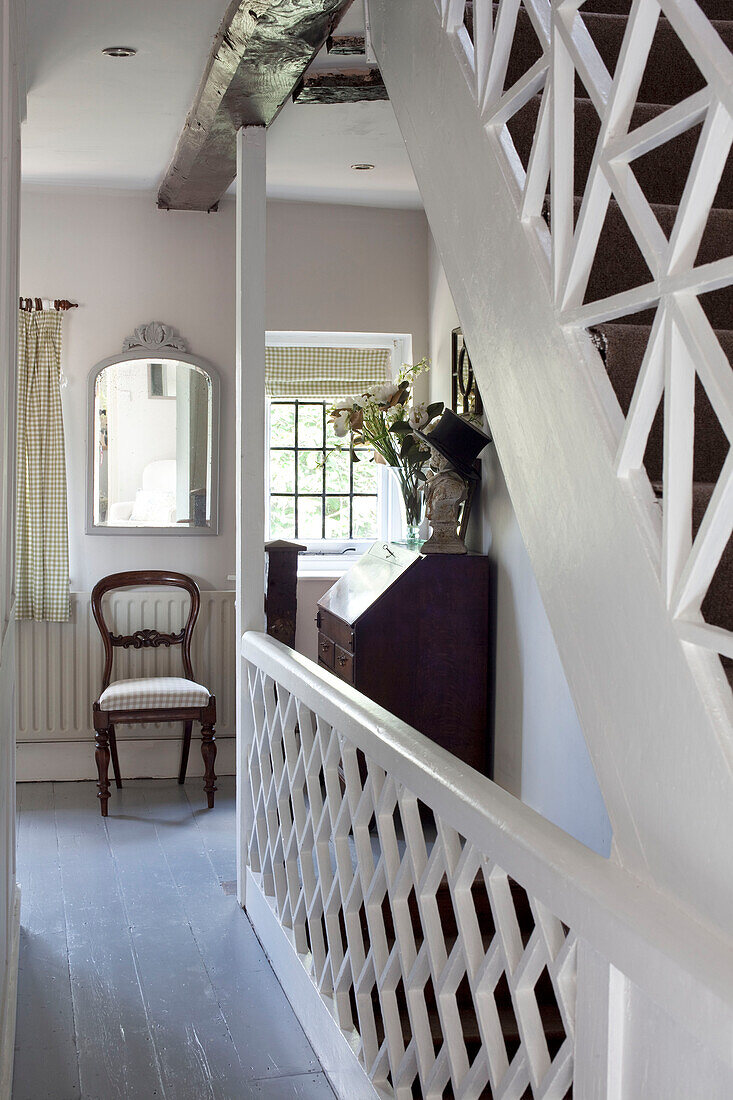 Wooden chair in landing hallway with banister trellis, West Sussex home, England, UK