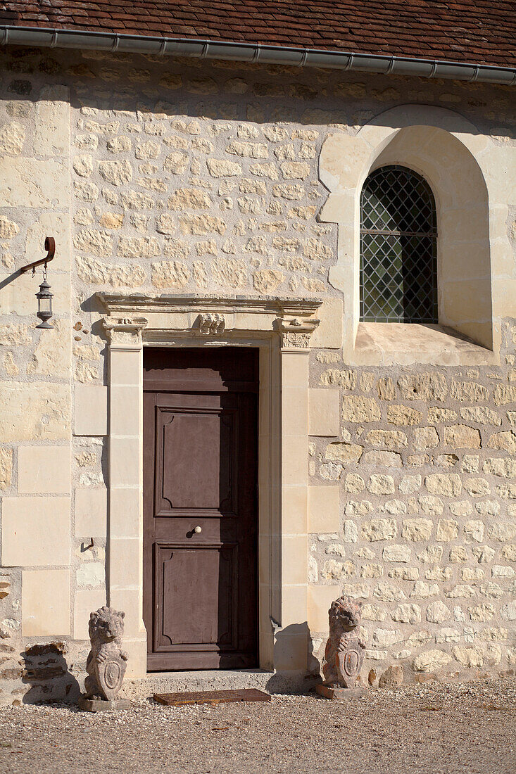Brown front door and arched window in stone exterior of French farmhouse in the Loire France