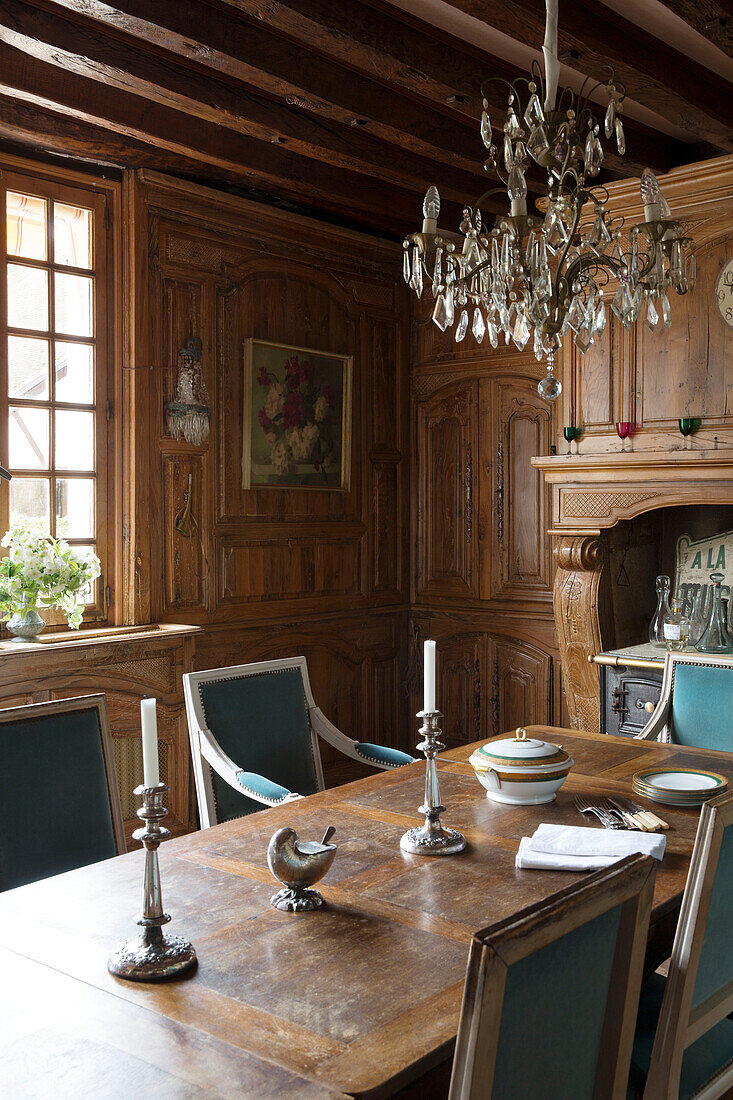 Silberbesteck auf einem hölzernen Esstisch unter einem Glaslüster in einem französischen Bauernhaus an der Loire, Frankreich, Europa