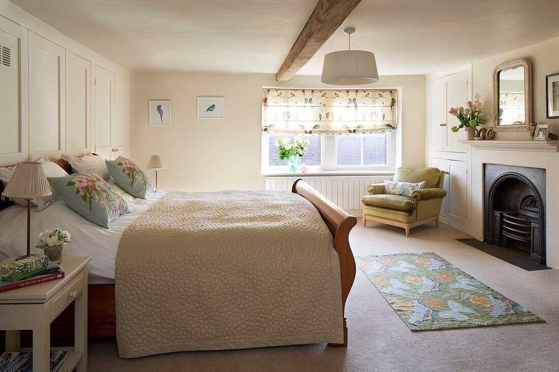 Quilted double bed with fireplace and beamed ceiling in London home England UK