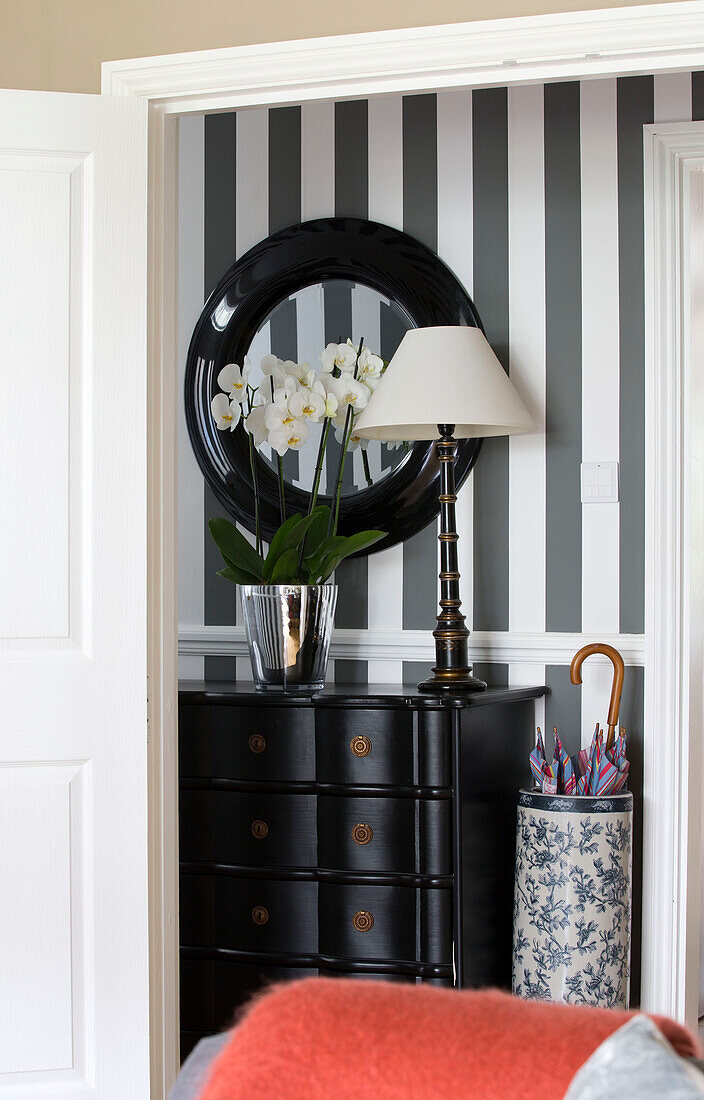 Spiegel über Sideboard in schwarz-weiß gestreiftem Flur eines Hauses in London, England, UK