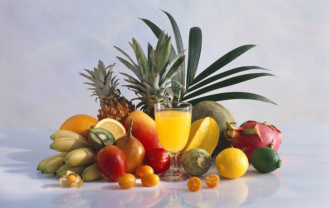 A glass of fruit juice and various fresh fruits